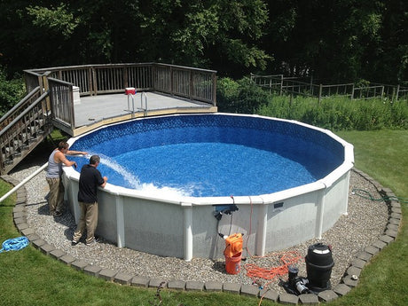 People filling an above-ground pool with water