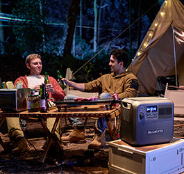 Two men camping with a Bluetti portable generator next to their tent