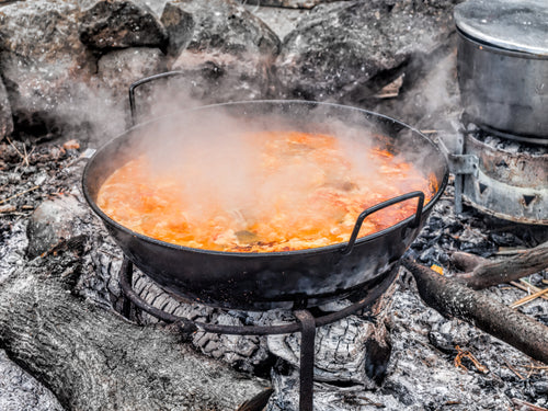 Campfire cooking with a large pot of stew over an open flame